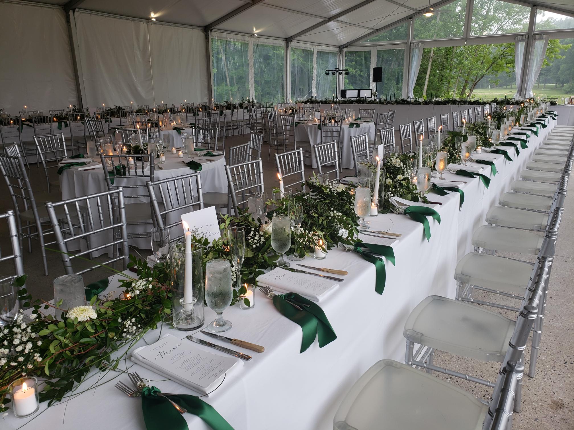 Long banquet tables set for a wedding reception under the tent